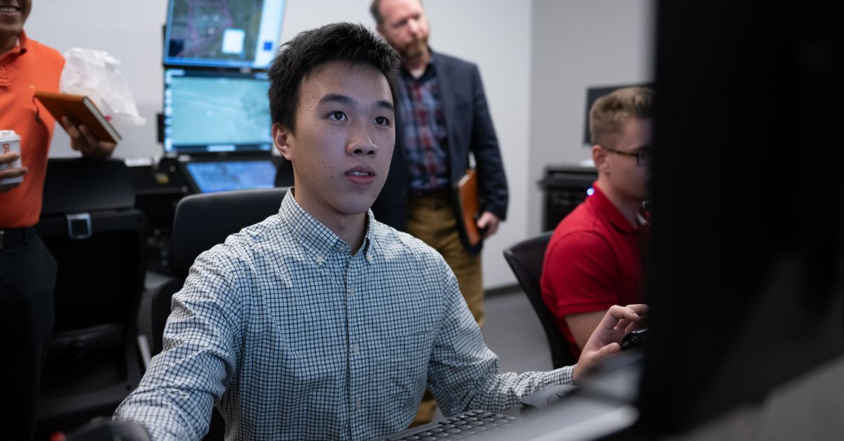 Student looks at big computer screen as others watch